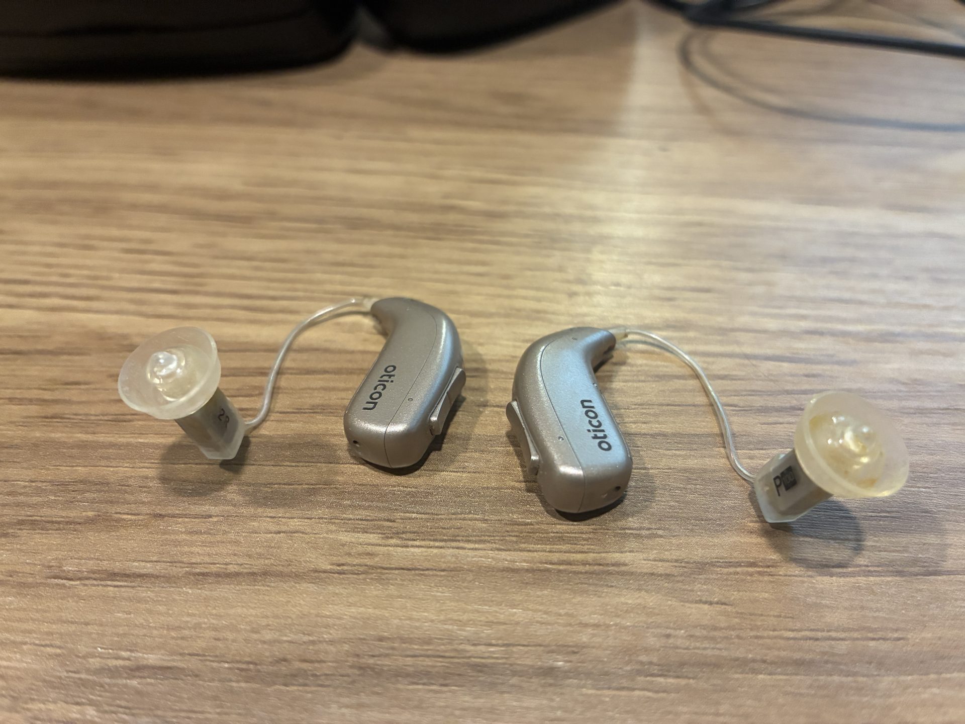 two RIC hearing aids sitting on a desk with dome flipped inside out