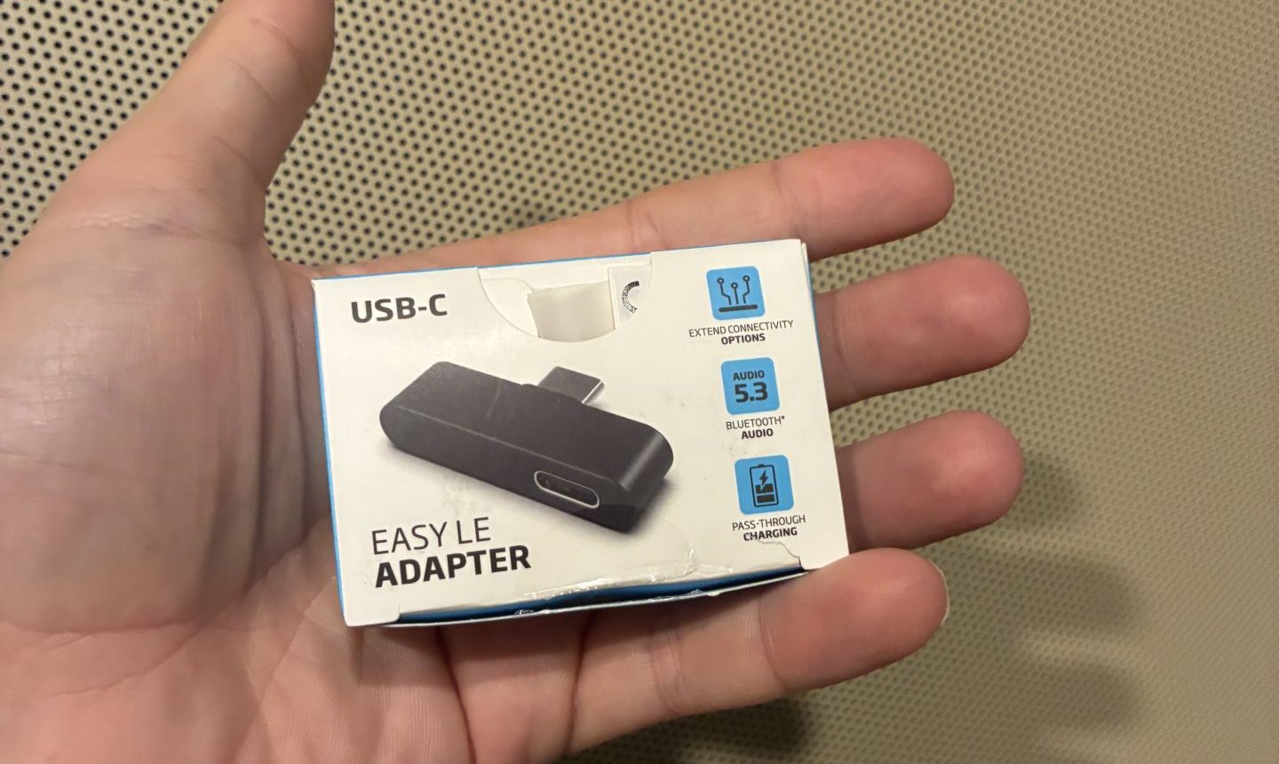 a hand hold new package of Oticon LE adapter unopened