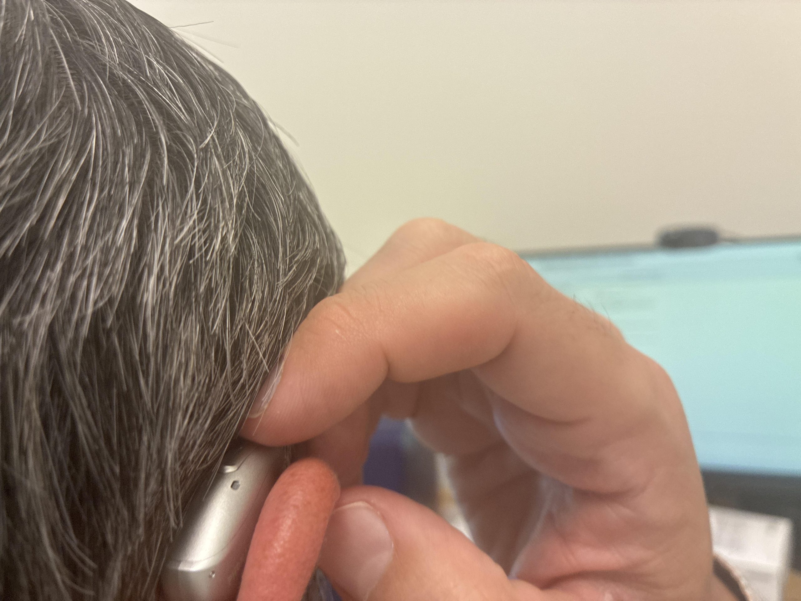 phonak audeo sphere hearing aid on ear, hand pushing down button to adjust